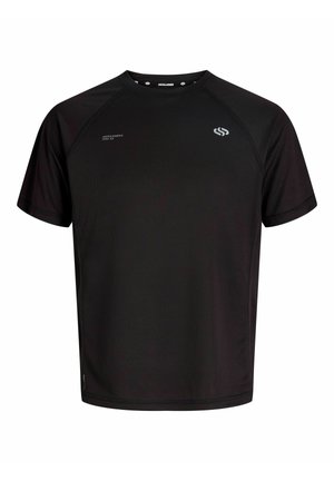 Garçon blond debout et souriant, portant un maillot de sport noir, un short noir avec des leggings noirs en dessous, des baskets blanches et des chaussettes blanches avec des rayures noires.