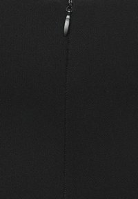 Tissu noir avec une texture lisse, présentant une couture verticale et une fermeture éclair en haut. Design minimaliste, sans motifs ni accents.