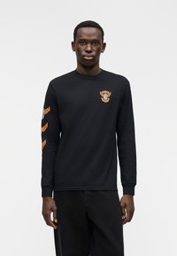 Maglietta nera a maniche lunghe in cotone con logo frontale e disegni alari arancioni su entrambe le maniche. Girocollo e polsini a coste.