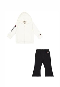 Sudadera blanca con cremallera y capucha, junto con pantalones negros, ambos con acentos del logo de Champion. Tejido suave, corte holgado con perneras acampanadas.