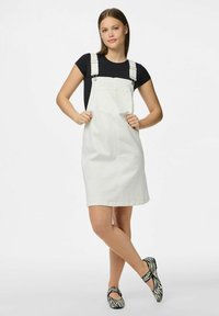 Beli denim overall obleka z nastavljivimi naramnicami in sprednjim žepom. Uklopljena z črnobele črtaste balerinke. Gladka tekstura.