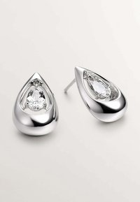 Pendientes en forma de lágrima de plata que presentan una gema alargada y clara, colocada en una caja de plata pulida y reflectante, exhibiendo una textura suave.