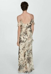 Maxi-jurk in lichtbeige met abstracte bruine patronen, voorzien van dunne spaghettibandjes en gerimpelde accenten langs de halslijn en onderrand.