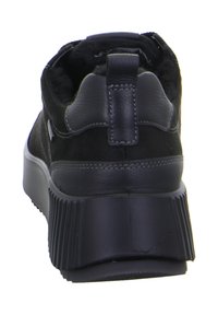 Zapatilla negra con parte superior de cuero liso y ante, suela plataforma de goma texturizada y lengüeta en el talón para facilitar su colocación.