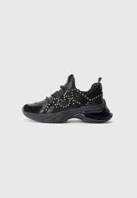 Zwarte sneakers met een mix van gladde en suede texturen, versierd met gouden studs en een chunky zoolontwerp voor extra hoogte.