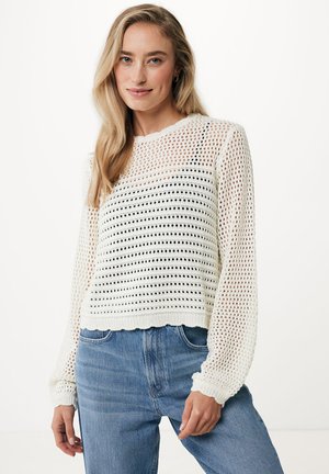 Witte gebreide trui met open geweven patroon, lange mouwen, ronde halslijn, golvende zoom, gecombineerd met blauwe high-waisted jeans.