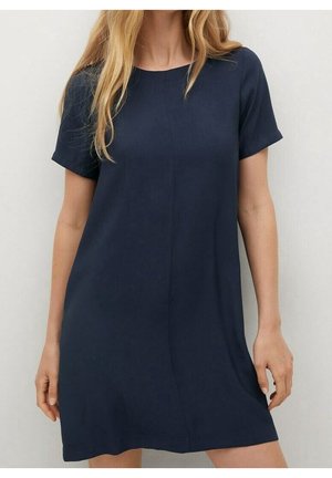 Femme portant une robe simple bleu marine, à manches courtes et longueur au genou, avec un col rond, sur un fond uni.