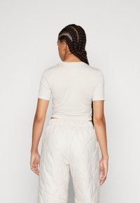 Jasnobeżowy krótki t-shirt z krótkimi rękawami i okrągłym dekoltem, zestawiony z jasnymi, pikowanymi spodniami do spania.