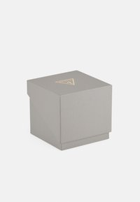 Graue Texturbox mit einem dreieckigen goldenen Logo auf der Oberseite. Verfügt über ein gefaltetes Klappen-Design und eine quadratische Basis.
