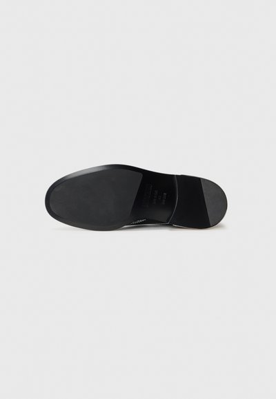 Black shoe sole with smooth texture, rounded shape, and minimal tread. Side features a slight heel with subtle branding detail.