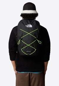 Mustapieni reppu neonvihreällä joustavaranka-muotoilulla. Ominaisuuksina The North Face -logo ja "Jester"-teksti alareunassa. Kankaan pinta on teksturoitu.