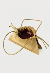 Borsa in camoscio giallo senape con coulisse, dalla forma triangolare. Interno con fodera rosso scuro e piccola etichetta del marchio. Manico lungo.