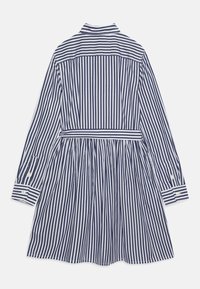 Košilové šaty s dlouhým rukávem v námořnické modré a bílé svislé pruhy, pruhovaný límec, zapínací manžety a odpovídající pásek v pase.