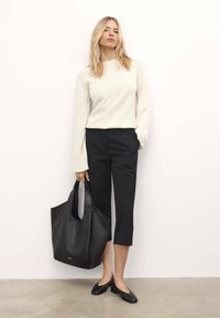 Pulover tricotat bej cu mâneci lungi, pantaloni negri scurți și geantă din piele neagră. Pantofii cu toc bloc negru completează ținuta.