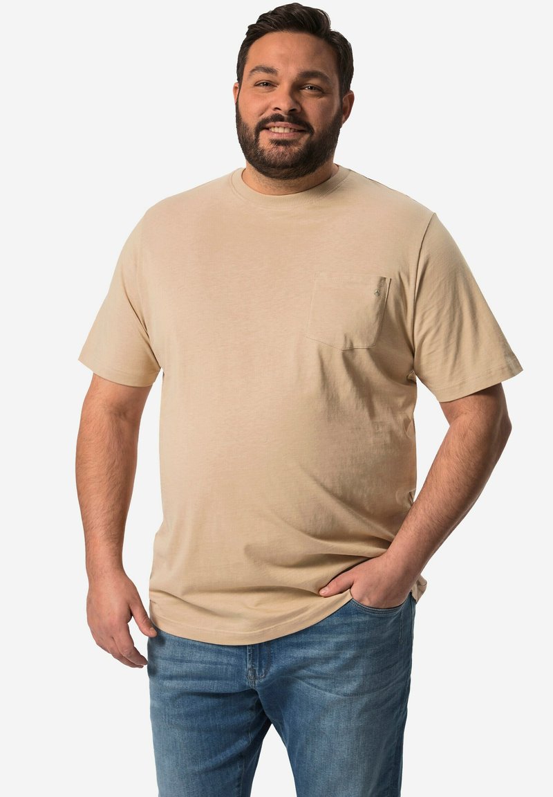 Beige tričko s krátkým rukávem, s přední kapsou, kulatým výstřihem a měkkou texturou, spárované s modrými džínami.