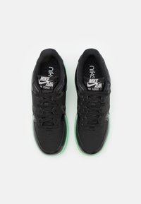 Svarta Nike Air Force 1-sneakers har en slät läderöverdel, svarta snören och en genomskinlig mintgrön sula. Framträdande logodetaljer på tungan.