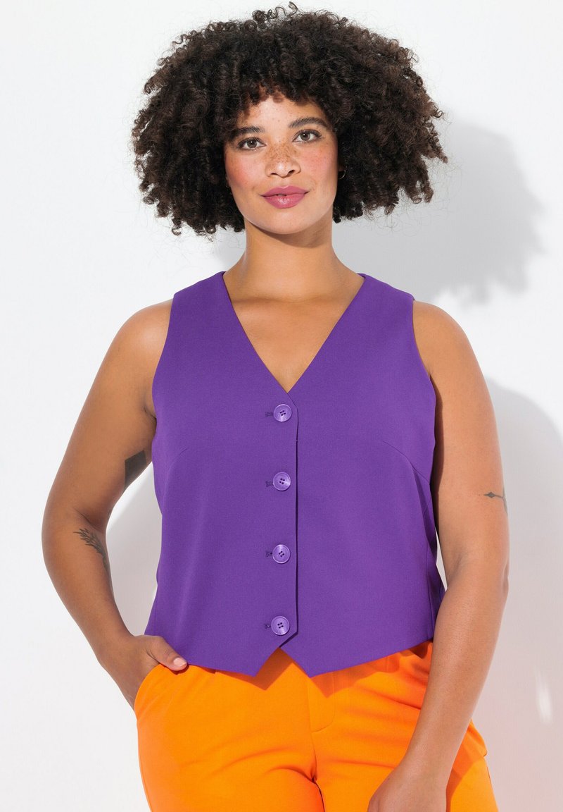 Gilet viola senza maniche con scollatura a V, caratterizzato da quattro bottoni tondi e un orlo leggermente curvato, abbinato a pantaloni arancioni.