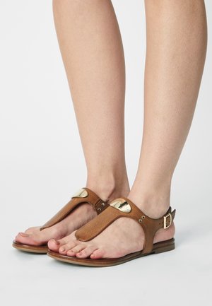 Sandales tissées marron avec boucle pour l’orteil, accents métalliques et bride de cheville ajustable ; semelle plate avec finition texturée.