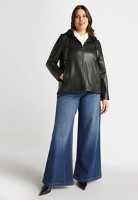 Svart imitation läderjacka med huva, dragkedjestängning och glittrande detaljer. Matchas med vida blå jeans och svarta spetsiga skor.