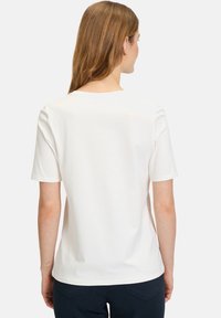 White short-sleeve t-shirt with a round neckline and a smooth texture, viewed from the back. Tailored fit with minimal details.