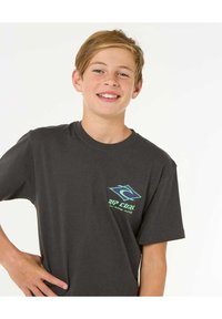 Camiseta de algodón gris oscuro, de manga corta, con cuello redondo, que presenta un logo en azul y verde en contraste en el lado izquierdo del pecho.