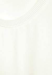 Vit texturerad tyg med rundad halsringning och ribbad finish. Ytan verkar jämn och mjuk, vilket betonar enkelhet i designen.