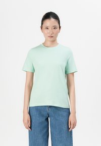 Mintgrønn bomulls t-skjorte med korte ermer, rund hals og løs passform, kombinert med lyseblå vide denimjeans.