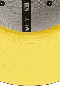 Gele baseballcap met een gladde textuur, voorzien van een zwarte binnenvoering, gelabeld met "59FIFTY" en "NEW ERA" branding.