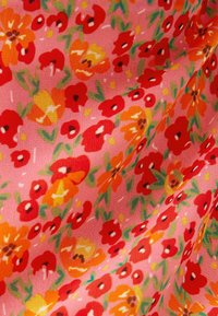 Kukallinen kangas, jossa on vaaleanpunainen tausta ja punaisia, oransseja sekä keltaisia kukkia. Siinä on myös vihreitä lehtiä ja hienovaraisia valkoisia yksityiskohtia.