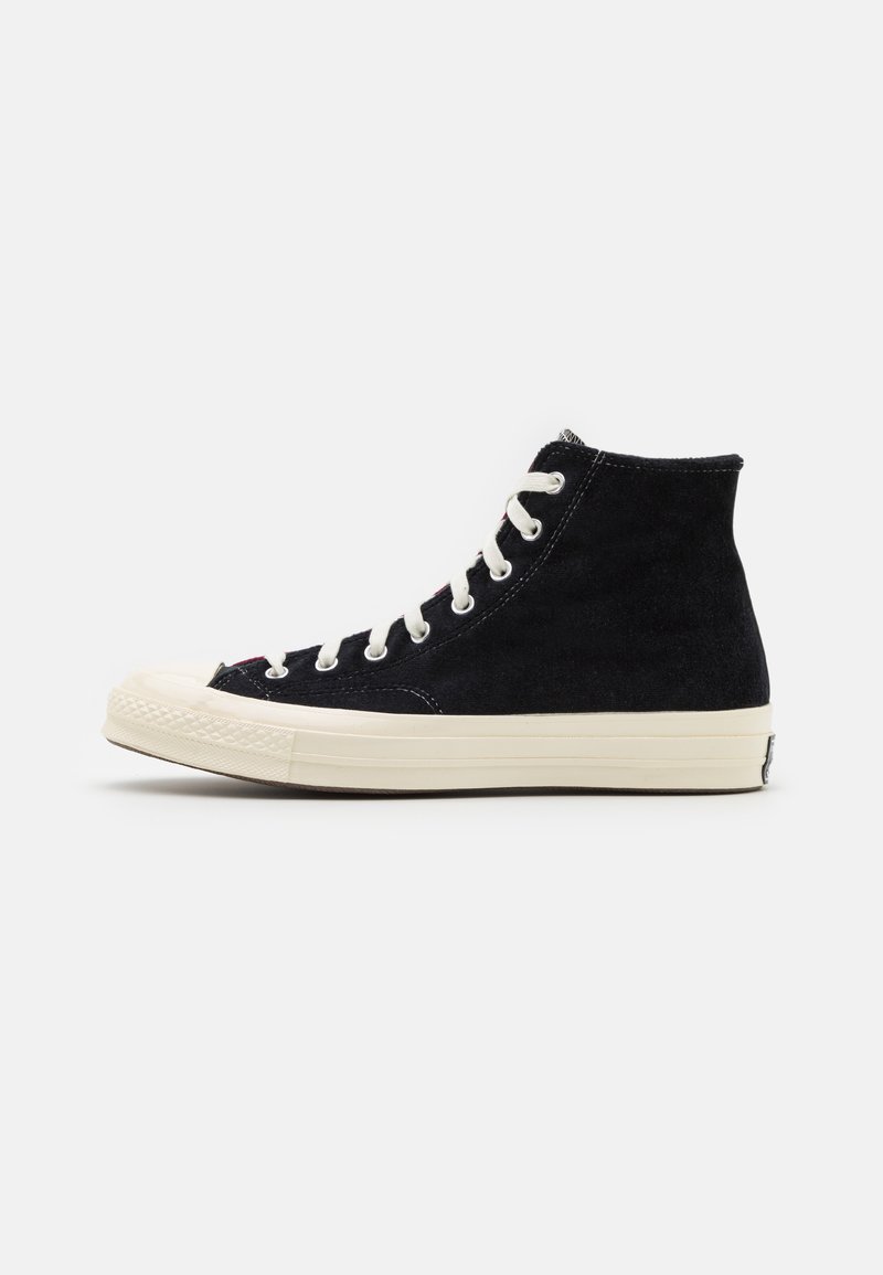 Baskets montantes en daim noir avec des lacets blancs, semelle en caoutchouc crème, bout arrondi et logo classique à l'arrière.