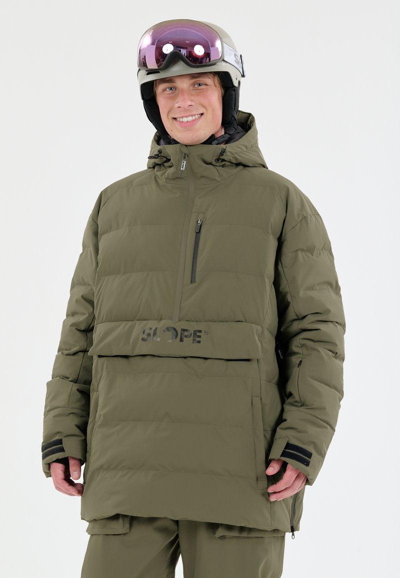 Grøn pufferjakke med horisontal quiltet design, frontlomme med lynlås, SLOPE-logo og justerbar hætte. Båret med hjelm og briller.