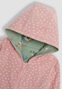 Sudadera rosa con pequeños patrones florales blancos, con forro interior verde con un diseño floral. Incluye cierre frontal con cremallera y capucha.