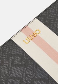 Liu Jo rahakott, millel on tekstuuriga must disain, sile kreemjas osa roosa triibuga ja kuldne bränding.