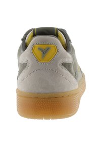 Baskets en suede grises et jaunes avec une semelle en caoutchouc texturée, arborant un logo en relief sur le talon et des détails d'accent contrastants.