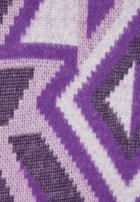 Primo piano di un tessuto lavorato a maglia con motivi geometrici in viola, lavanda e bianco e una superficie fluffy e texturizzata.