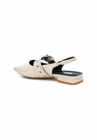 Zapato slingback de punta beige con una correa decorativa que presenta acentos metálicos, tacón bajo y textura de cuero suave.