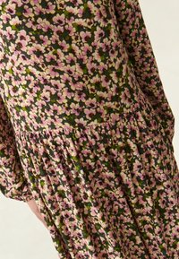 Blumenkleid mit dunkelgrünem Hintergrund und rosa sowie weißen Blumen. Vertikale Falten an der Taille und lange Ärmel. Leichter Stoff.