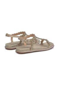 Vlakke sandalen met een lichtgouden metallic afwerking, versierd met swarovski's op de banden, met een geschulpte ontwerp en een verstelbare enkelgesp.