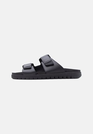 Black slide sandal with two adjustable hook-and-loop straps and a thick, grooved sole for casual wear.