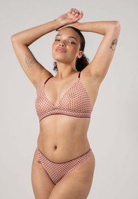 Rosa prickig bikini-set med en v-ringad bralette och matchande låg-midja bottom, med maroon detaljer och ett mjukt, texturerat tyg.