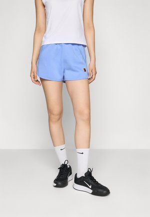 Pantalones cortos deportivos de color azul claro con un logo bordado, combinados con una camiseta sin mangas blanca, zapatillas negras y calcetines blancos con un logo.