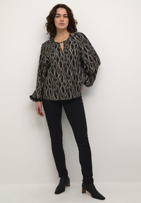 Svart mönstrad blus med nyckelhålsringning, texturerad tyg och puffärmar, som matchas med slim fit svarta byxor och ankelboots.