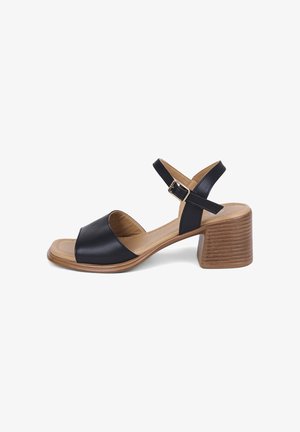 Black leather open-toe sandal with ankle strap, gold buckle, cushioned tan insole, and stacked wooden block heel.