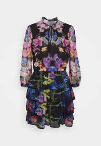 Kukkakuvioinen mekko, jossa on läpinäkyvää mustaa kangasta ja monivärisiä kukkakuoseja. Röyhelötierit ja kerätty pääntie, jossa on nauhatyylinen yksityiskohta.