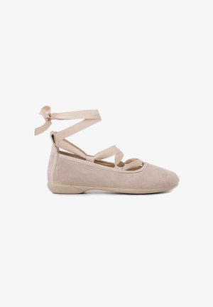 Scarpe da balletto in suede beige con cinturini incrociati alla caviglia, punte arrotondate e suola piatta in gomma. Texture liscia con dettagli di design minimi.