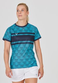 Tyrkis- och marinrandig sporttröja med korta ärmar, rund halsringning och strukturerat mönster; kombinerad med vita shorts med ett emblem.