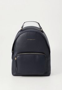 Navy leather backpack with rounded shape, gold-tone hardware, and a front zip pocket. Features top handle for carrying comfort.