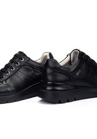 Zapatillas de cuero negro con punta redondeada, diseño de cordones y soporte acolchado en el tobillo. Presenta costuras sutiles y una suela negra gruesa.