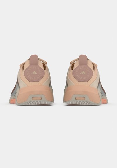 Scarpe da corsa leggere in tonalità beige e rosa con tomaia in mesh testurizzato, collarino imbottito nel tallone e dettagli in gomma sulla suola.