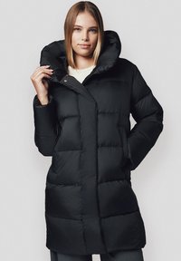 Czarna kurtka puchowa z dużym kapturem, pikowany design i zamek błyskawiczny z przodu. Posiada boczne kieszenie oraz luźny krój.